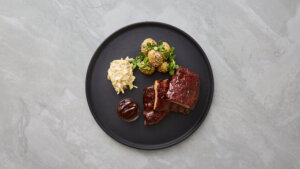 Langtidsbraiserede spareribs med kartofler, coleslaw og barbecuesauce.